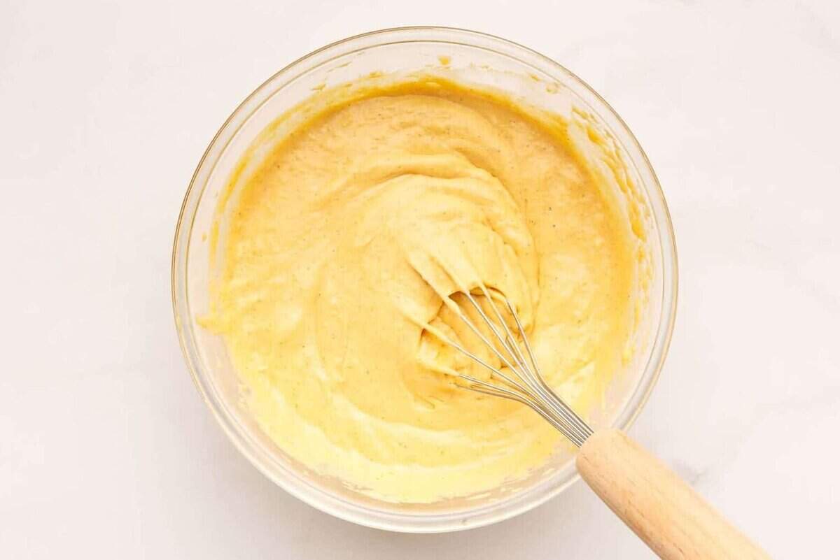 Mixing ingredients for sweet potato waffles in a glass bowl. 