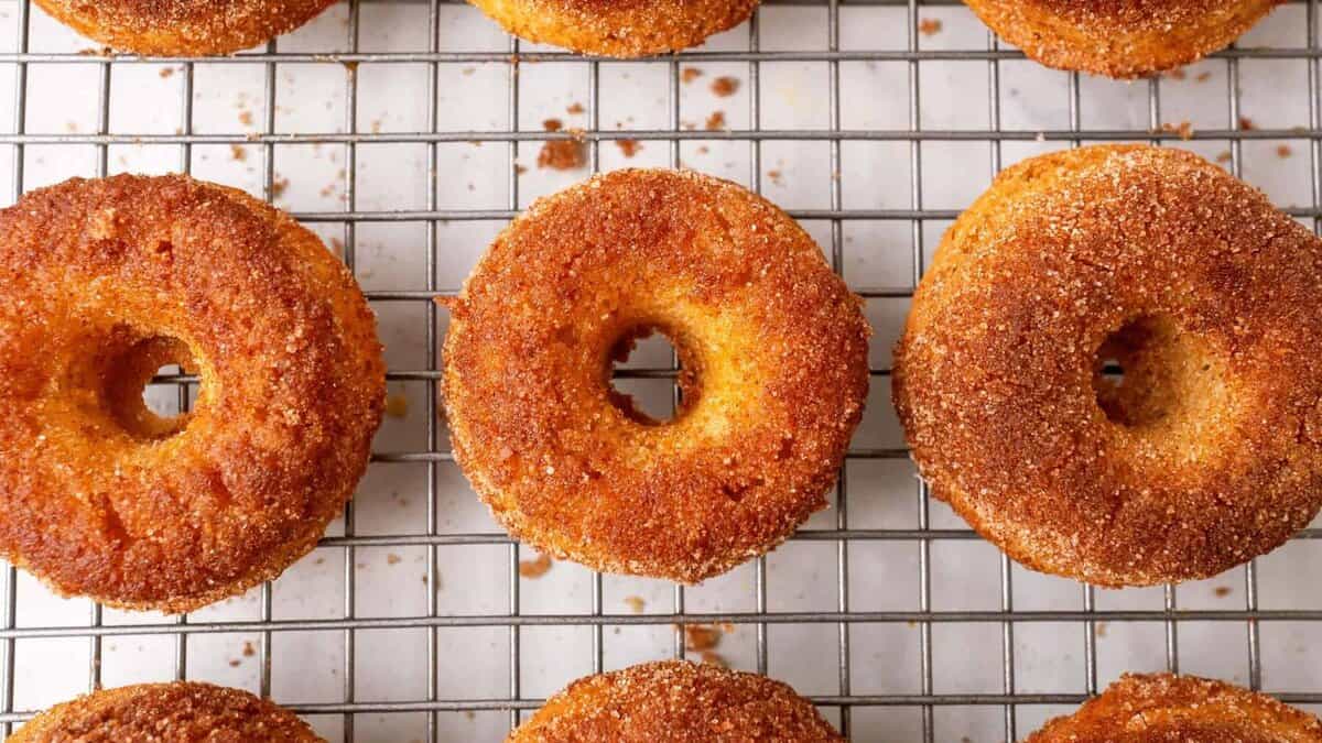 baked apple cider donuts sitting on a metal cooling rack.