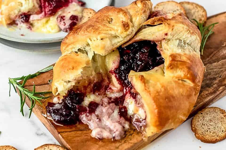 Baked brie on a cutting board surrounded by crackers.