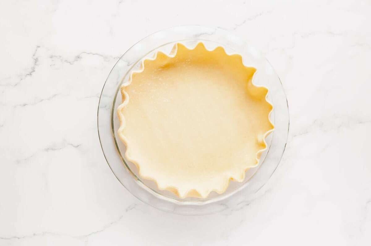 Unbaked pie crust in glass dish.
