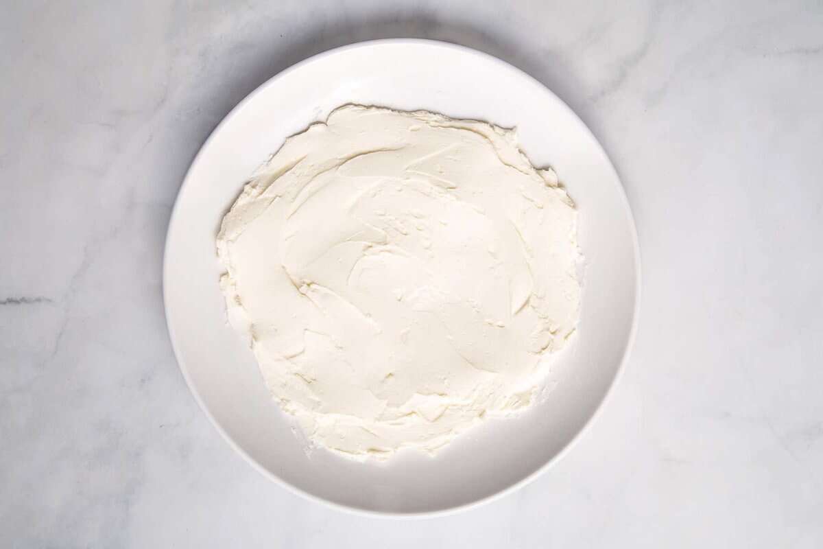 Cream cheese spread onto white plate.
