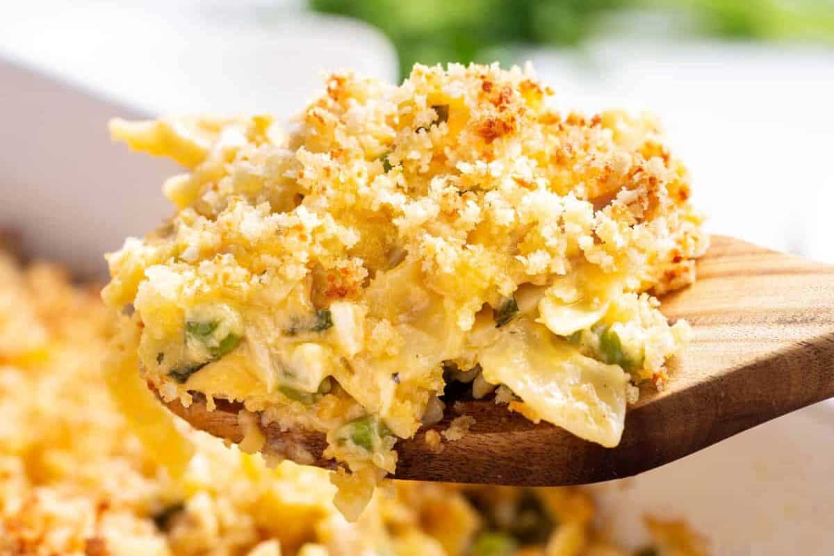 Leftover turkey casserole being scooped out of a baking dish on a wooden spoon.