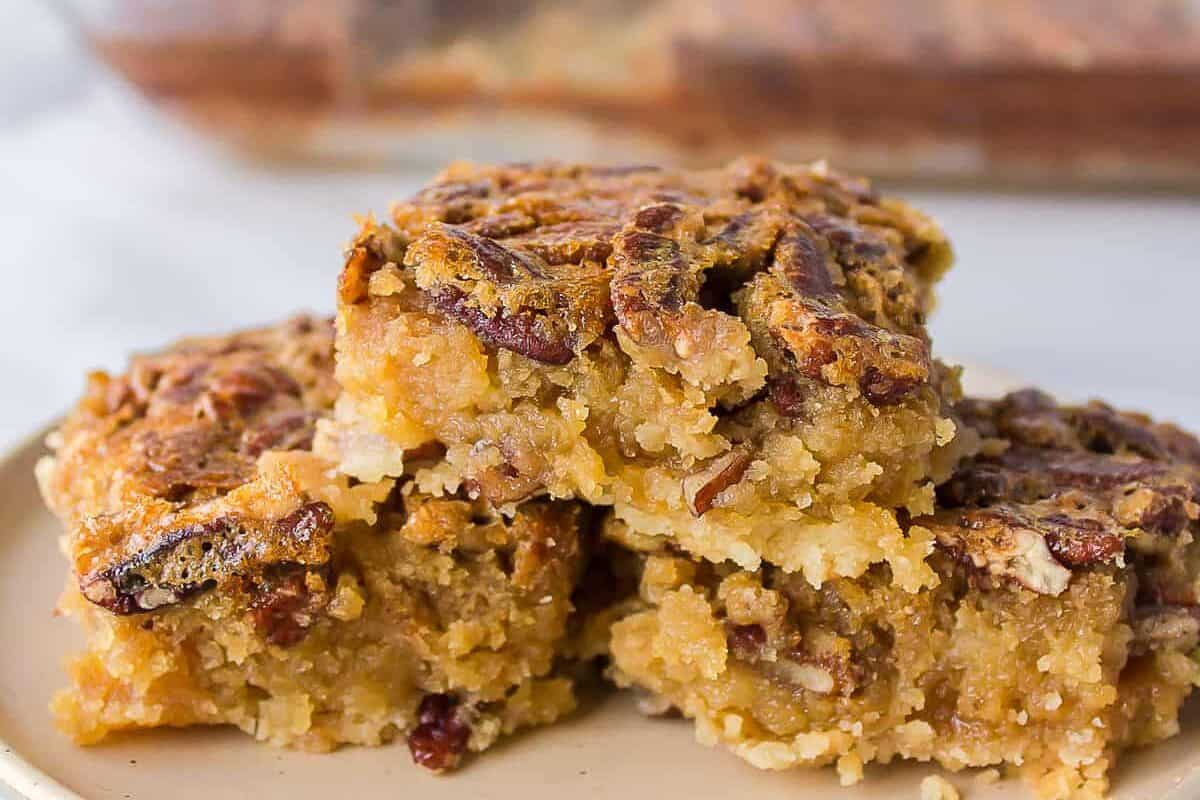 Three pecan pie bars still on a white plate.