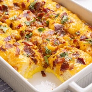 Bacon, egg and cheese biscuit casserole in casserole dish with one slice removed.