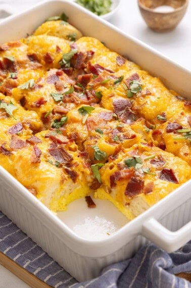 Bacon, egg and cheese biscuit casserole in casserole dish with one slice removed.