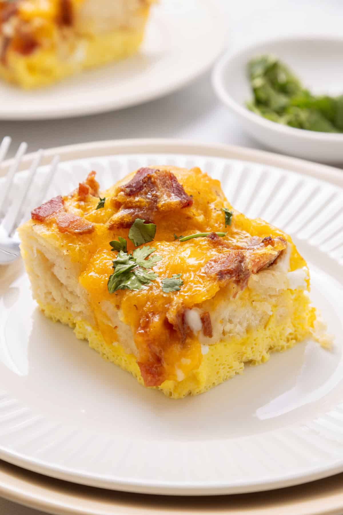 Slice of bacon, egg and cheese biscuit casserole on plate.
