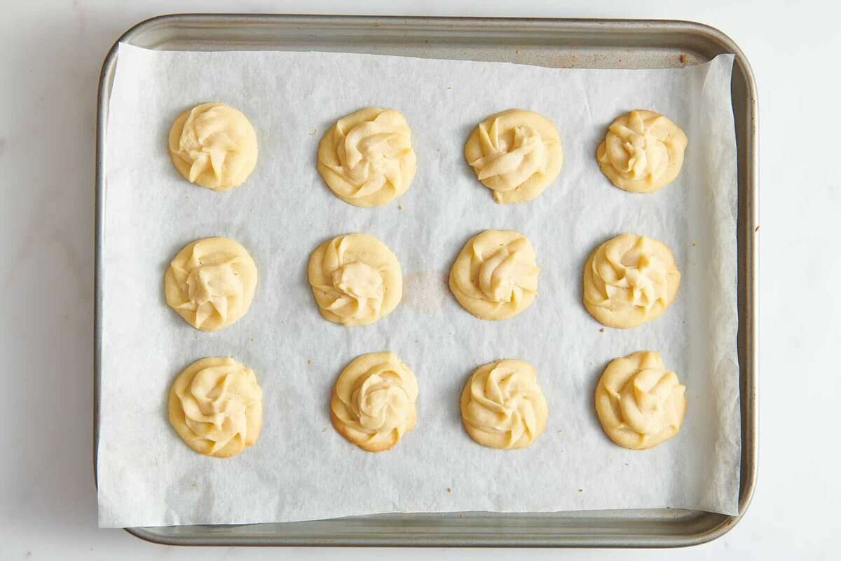 Christmas butter cookies on parchment lined baking sheet.