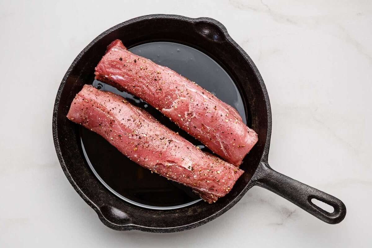 Pork tenderloins searing in skillet.