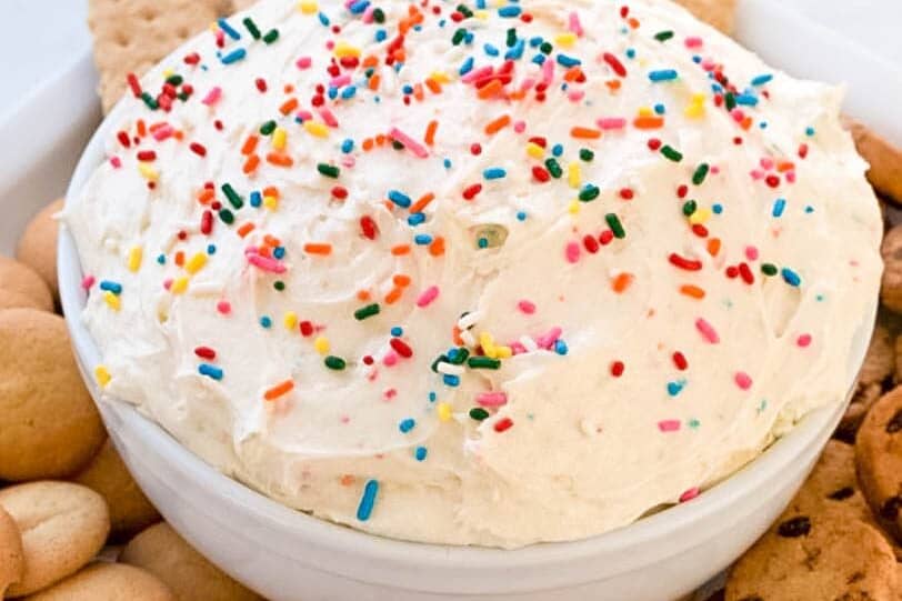 bowl of creamy fruit and cookie dip with animal crackers surrounding it