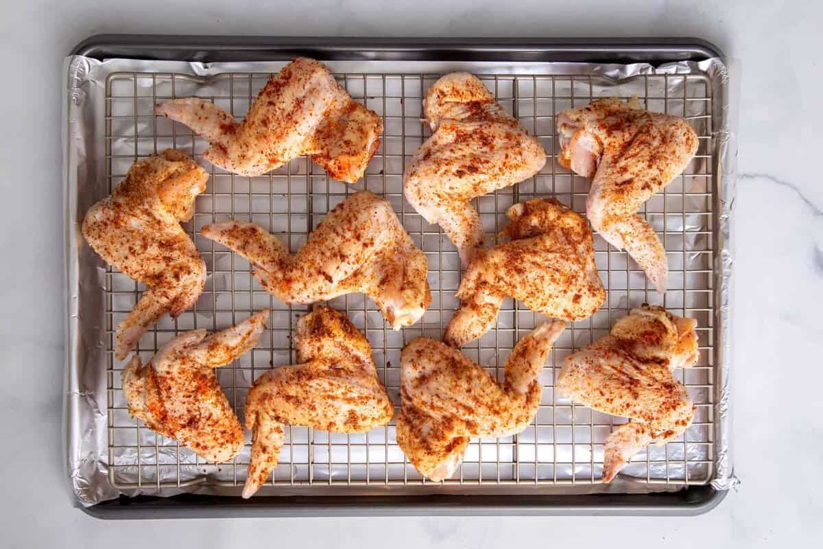 Seasoned chicken wings on wire rack before cooking.