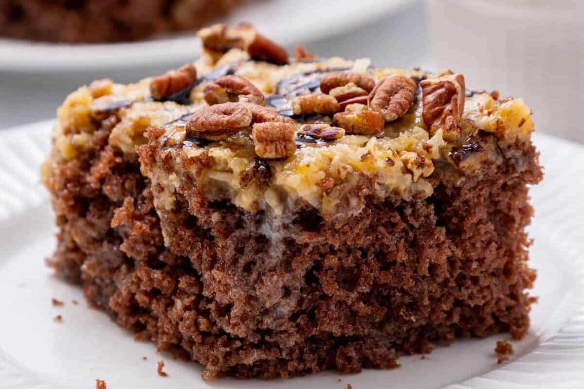 german chocolate poke cake slice on a white plate.