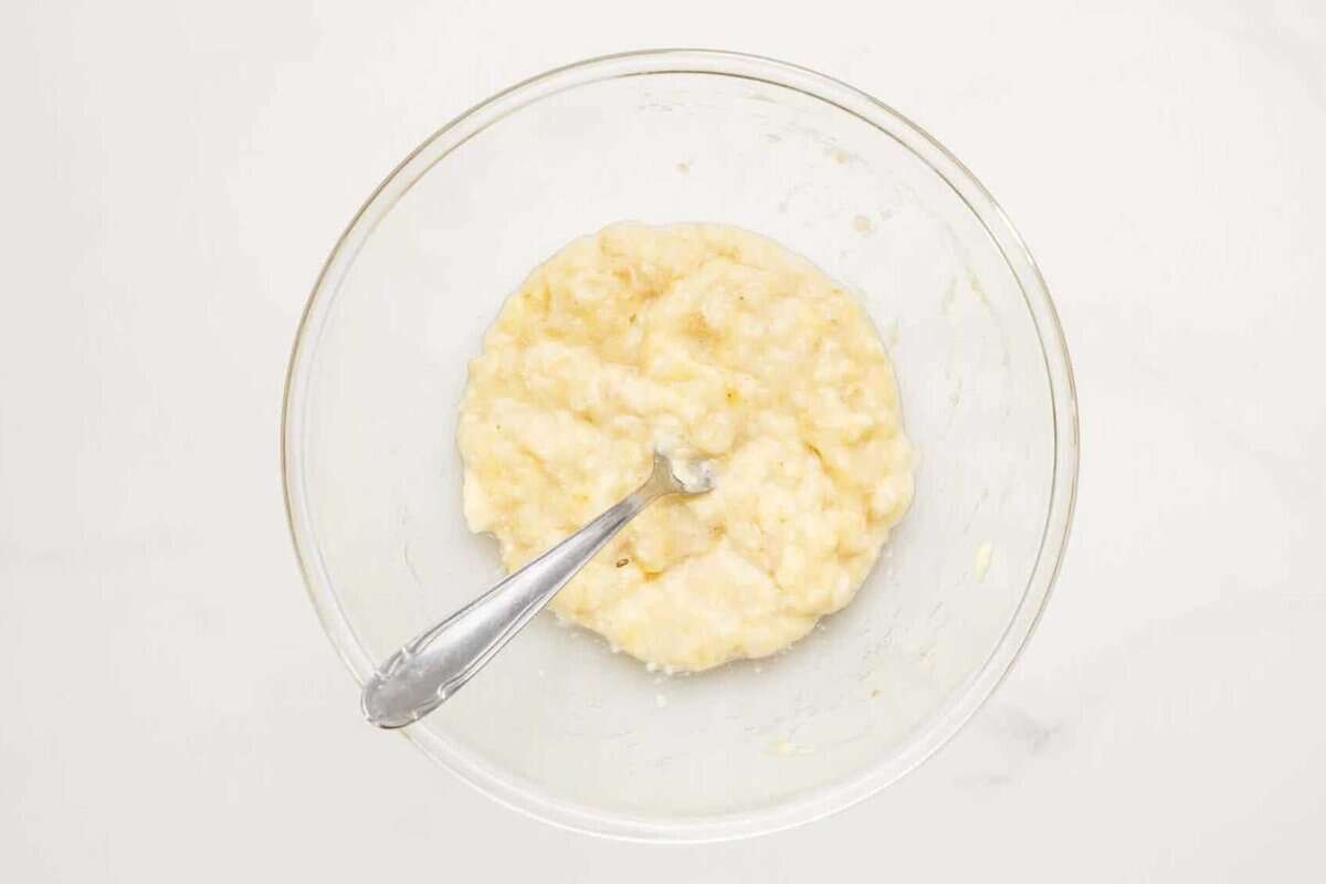 Mashed banana in bowl with fork.