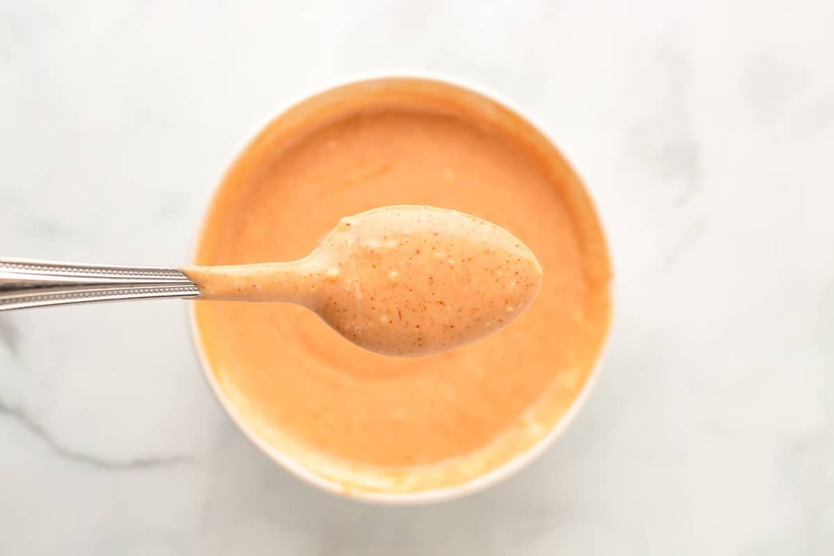 Spoonful of French fry sauce held over bowl.