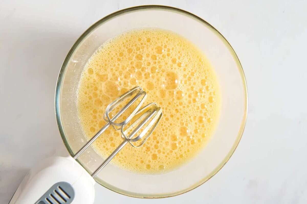 Electric mixer in bowl of eggs.