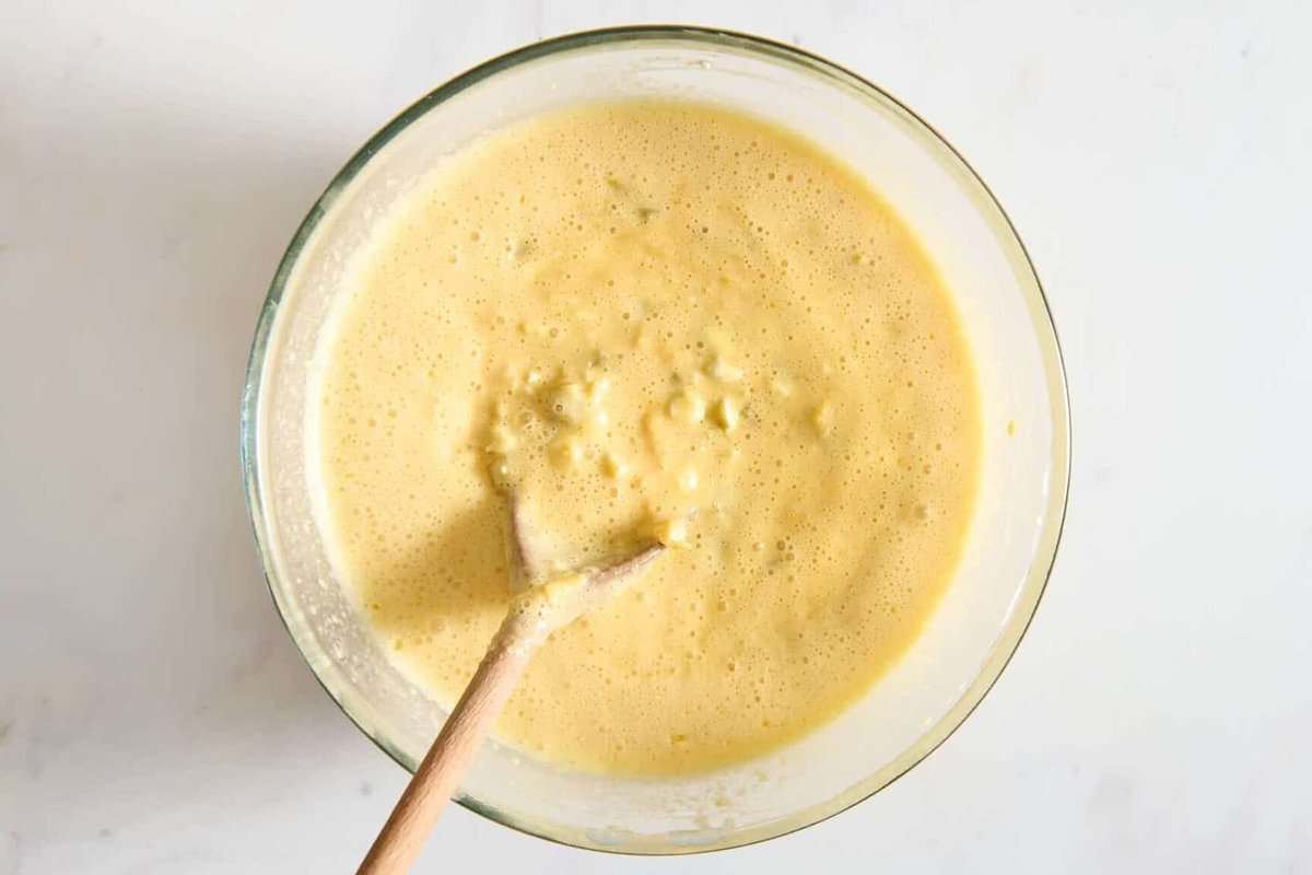 Egg and green chile mixture in bowl with wooden spoon.