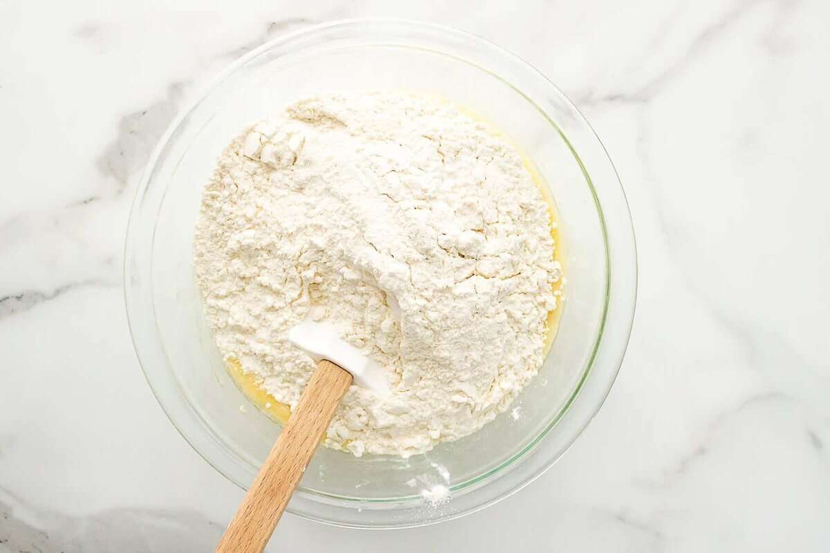 Combining wet and dry ingredients in bowl for banana muffins.