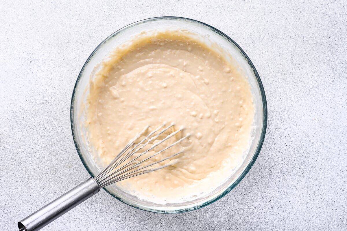 Pancake batter in glass bowl with whisk.