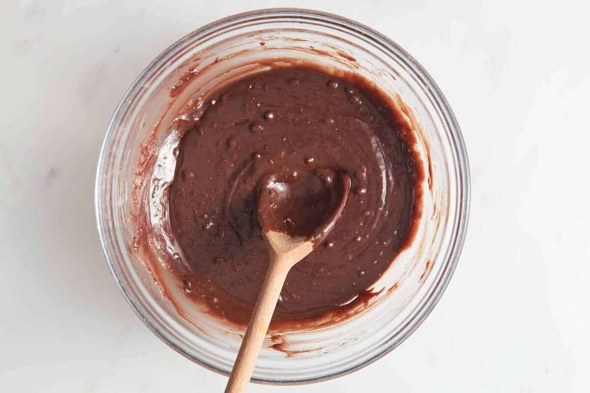 Brownie batter in bowl with wooden spoon.