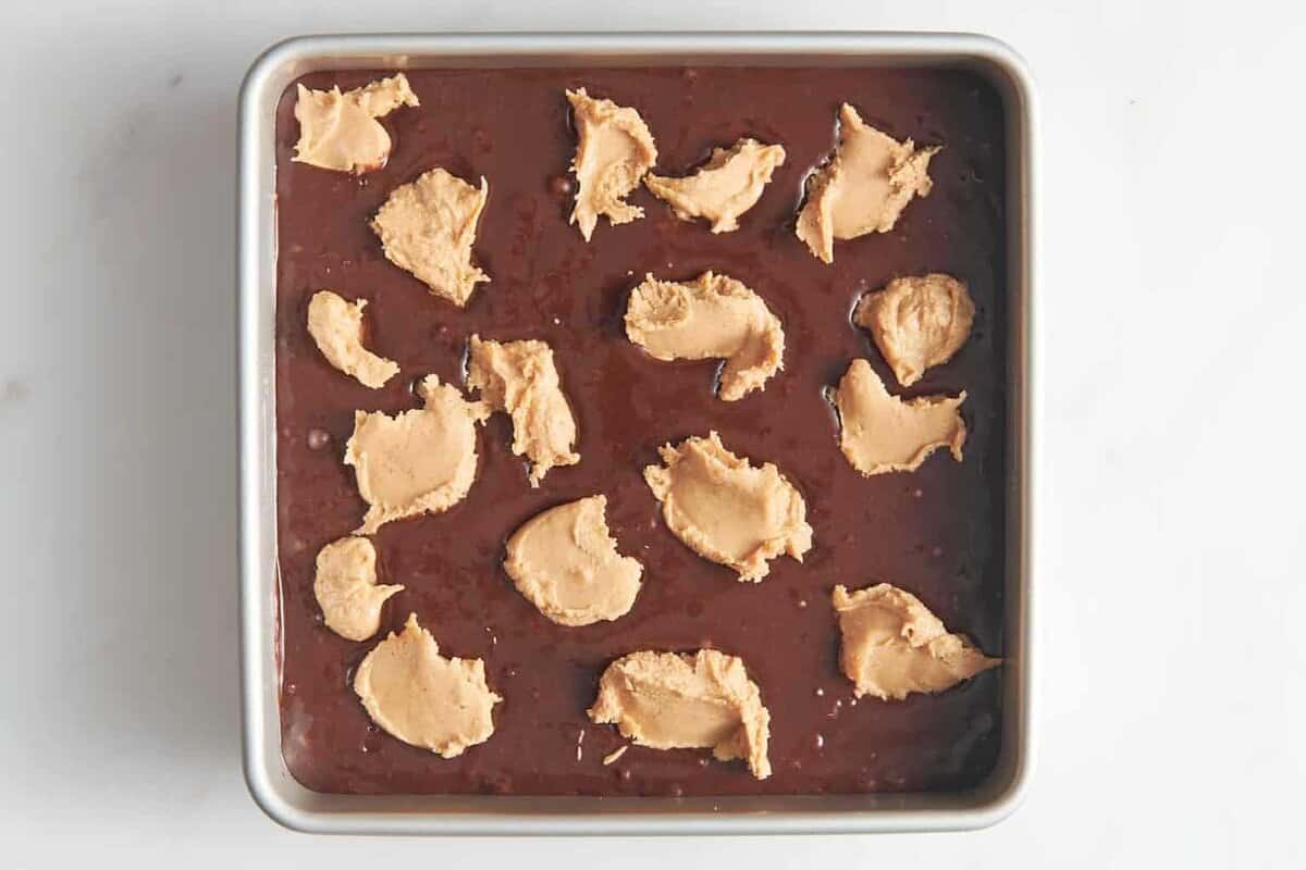 Dollops of peanut butter added to pan of brownie batter.