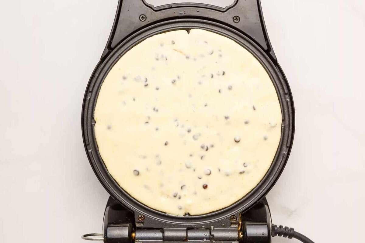 Chocolate chip waffle batter in waffle maker.