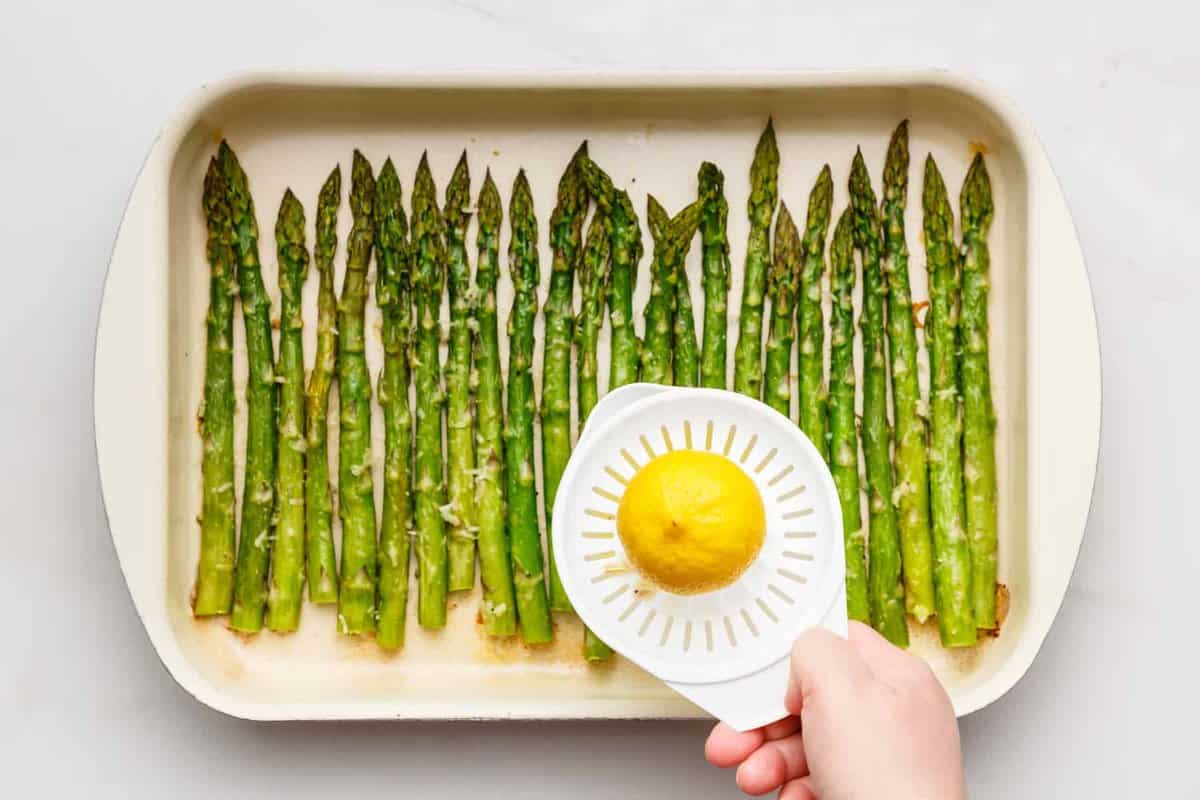 Squeezing lemon juice onto oven roasted asparagus.