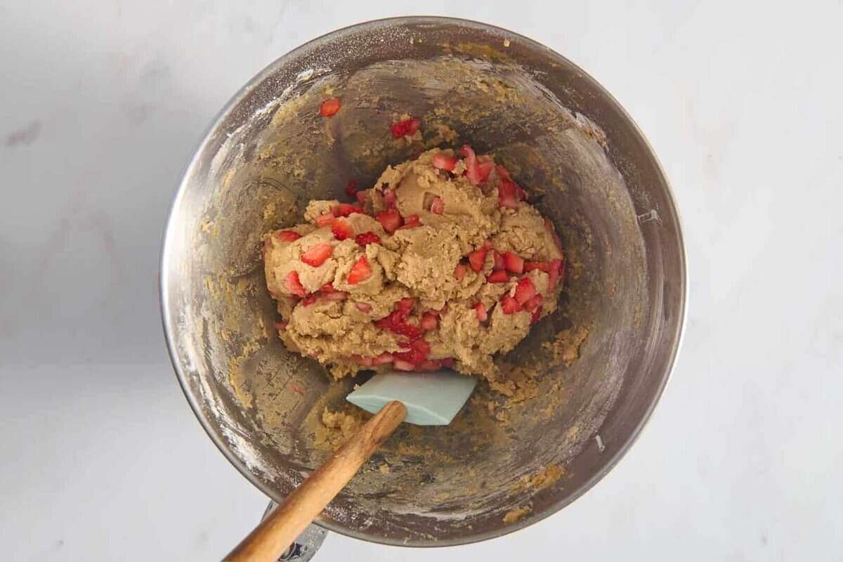 Strawberry cookie dough in bowl with rubber spatula.