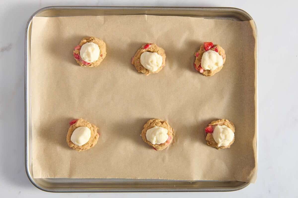 Cheesecake filling scooped onto strawberry cookie dough.