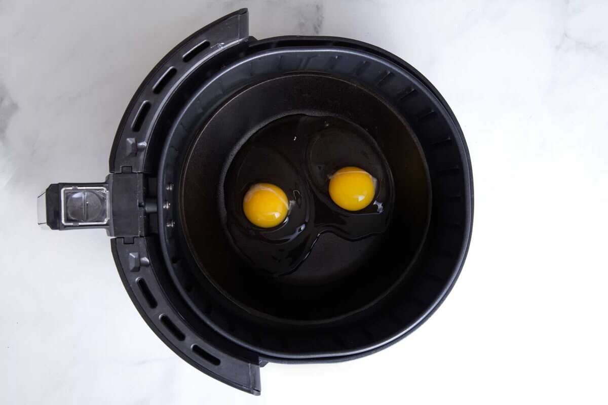 Eggs cracked in air fryer basket.