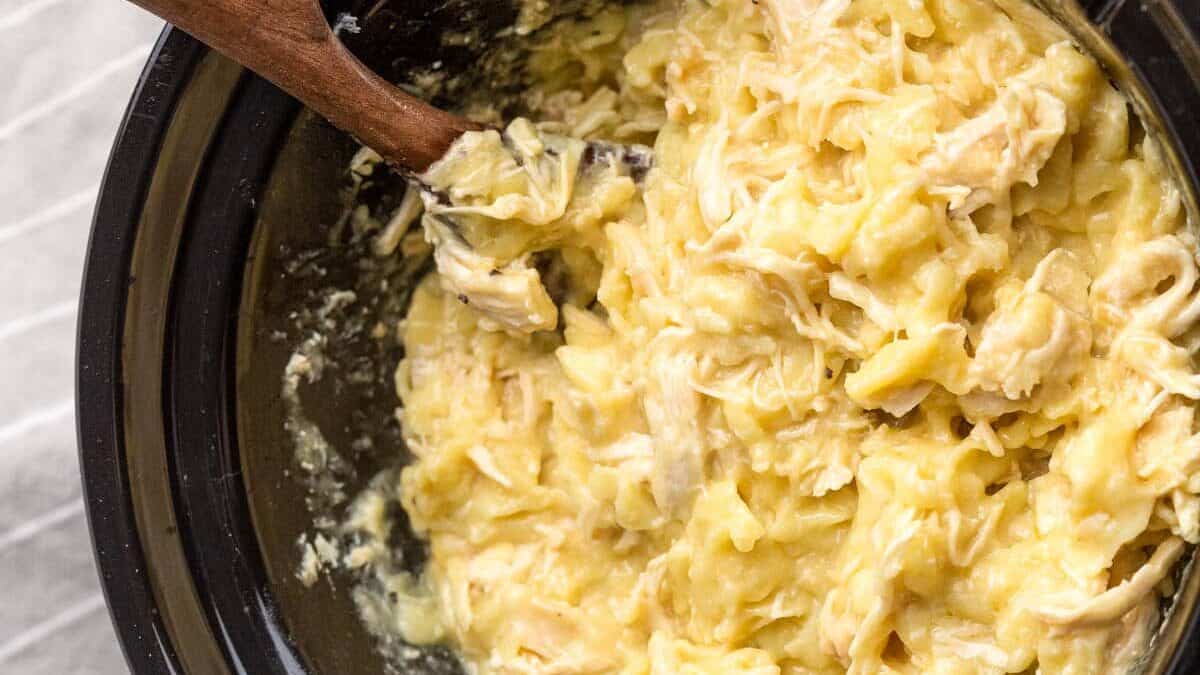 wooden spoon in a slow cooker full of chicken and noodles