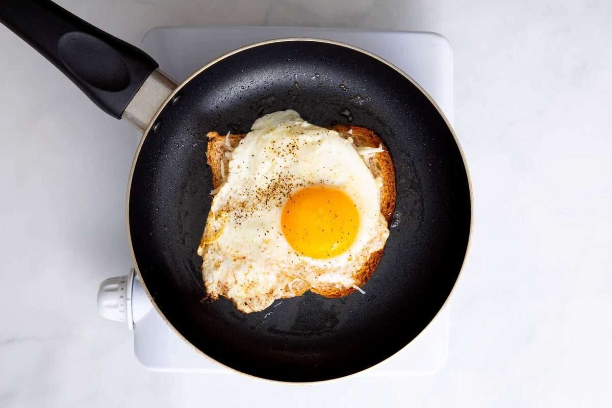 Fried egg on slice of bread in pan.
