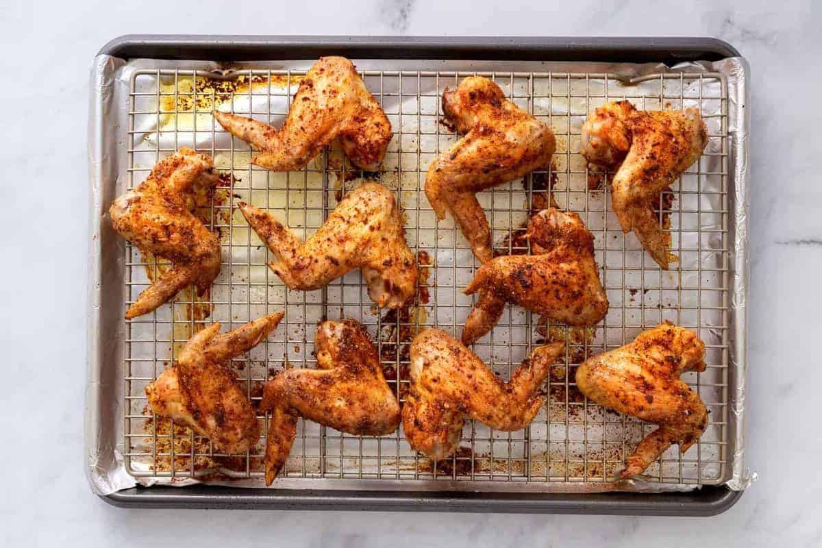 Cooked chicken wings on wire rack.