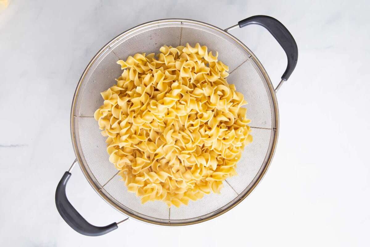 Cooked egg noodles in colander.