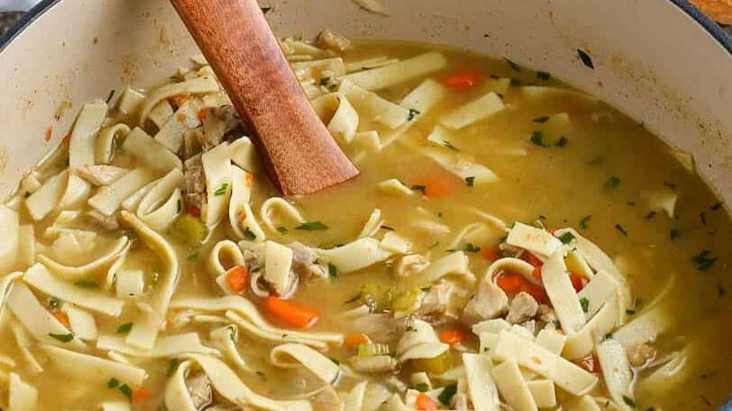 leftover turkey soup in a dutch oven with a wooden soup