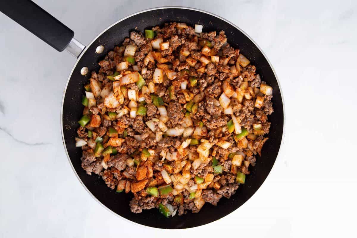 Ground beef and vegetables browning in skillet.