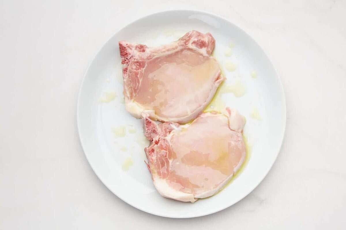 Bone-in pork chops drizzled with olive oil.