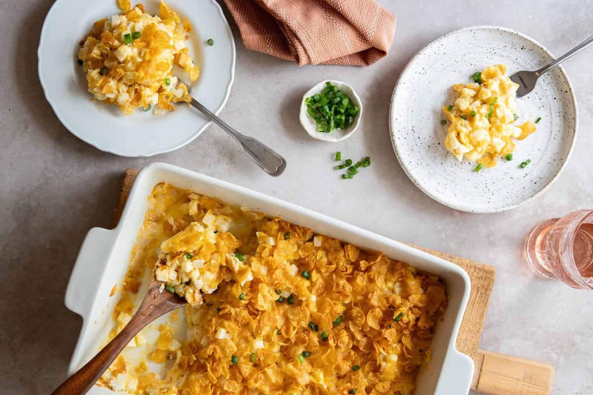 Overhead view of cheesy potatoes on 2 plates and in baking dish