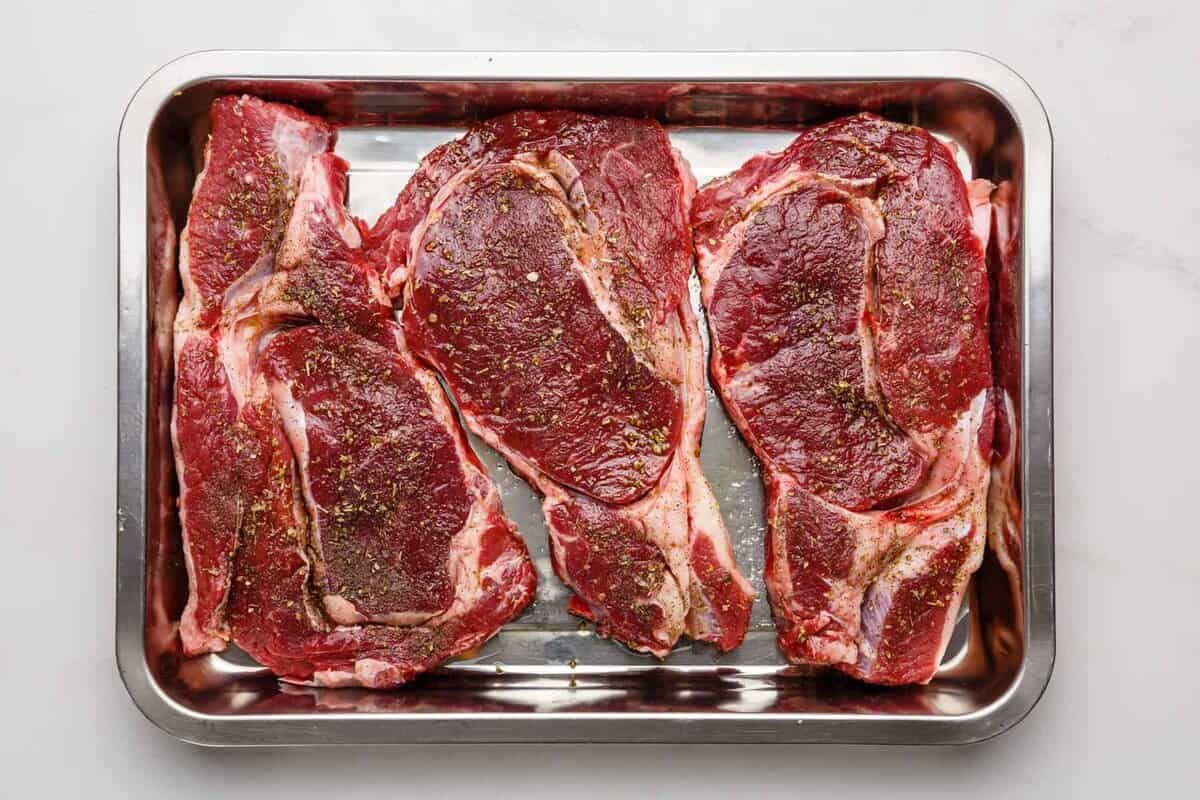 Ribeye steaks in roasting pan.
