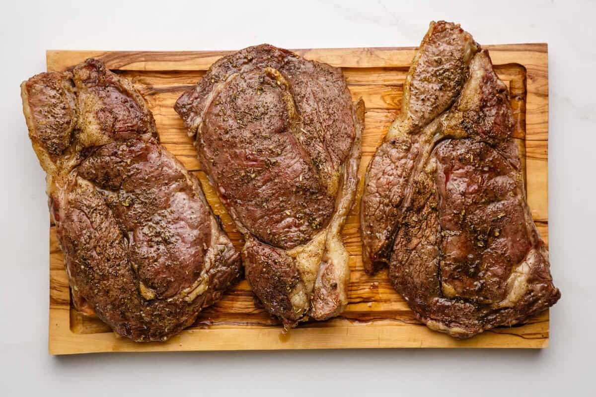 Cooked ribeye steaks on cutting board.