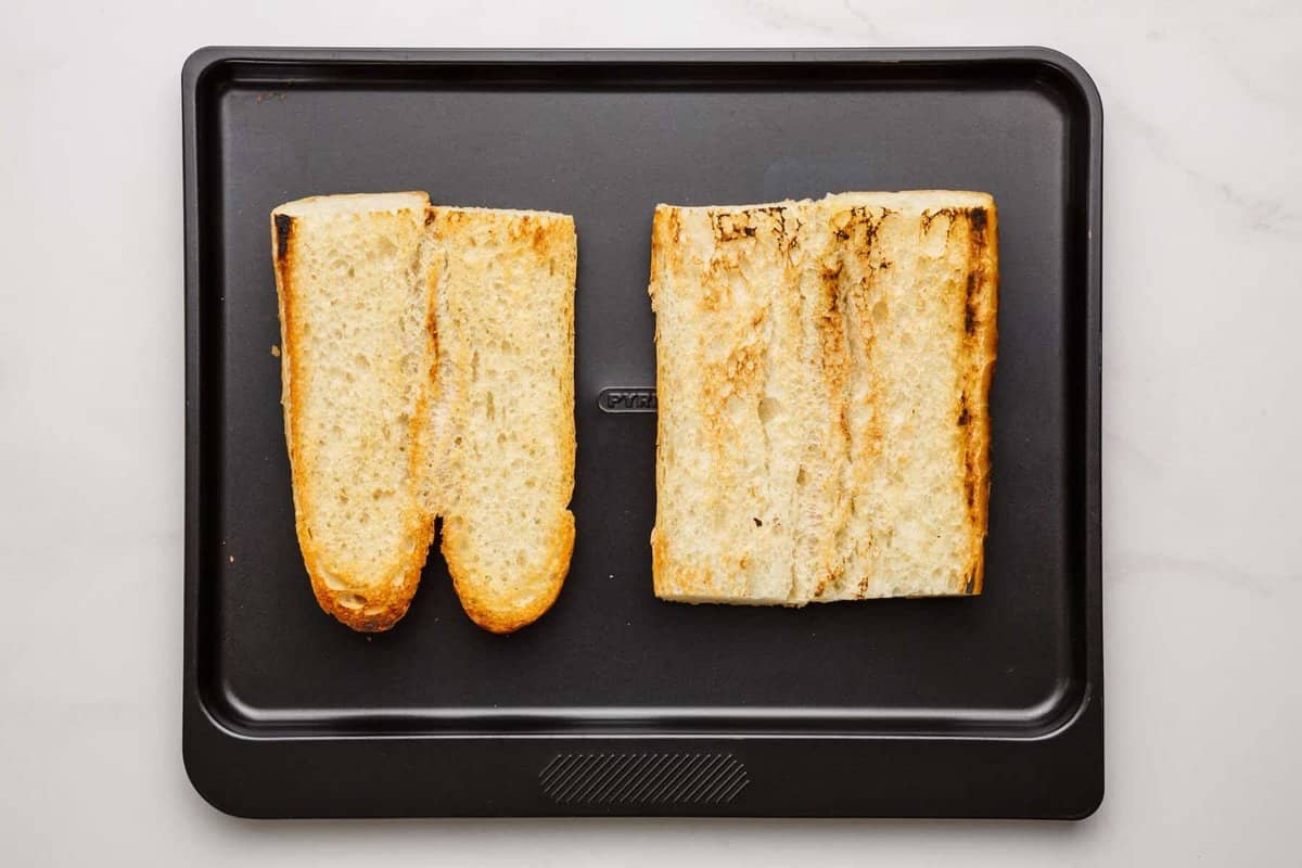 Toasted hoagie rolls on pan.