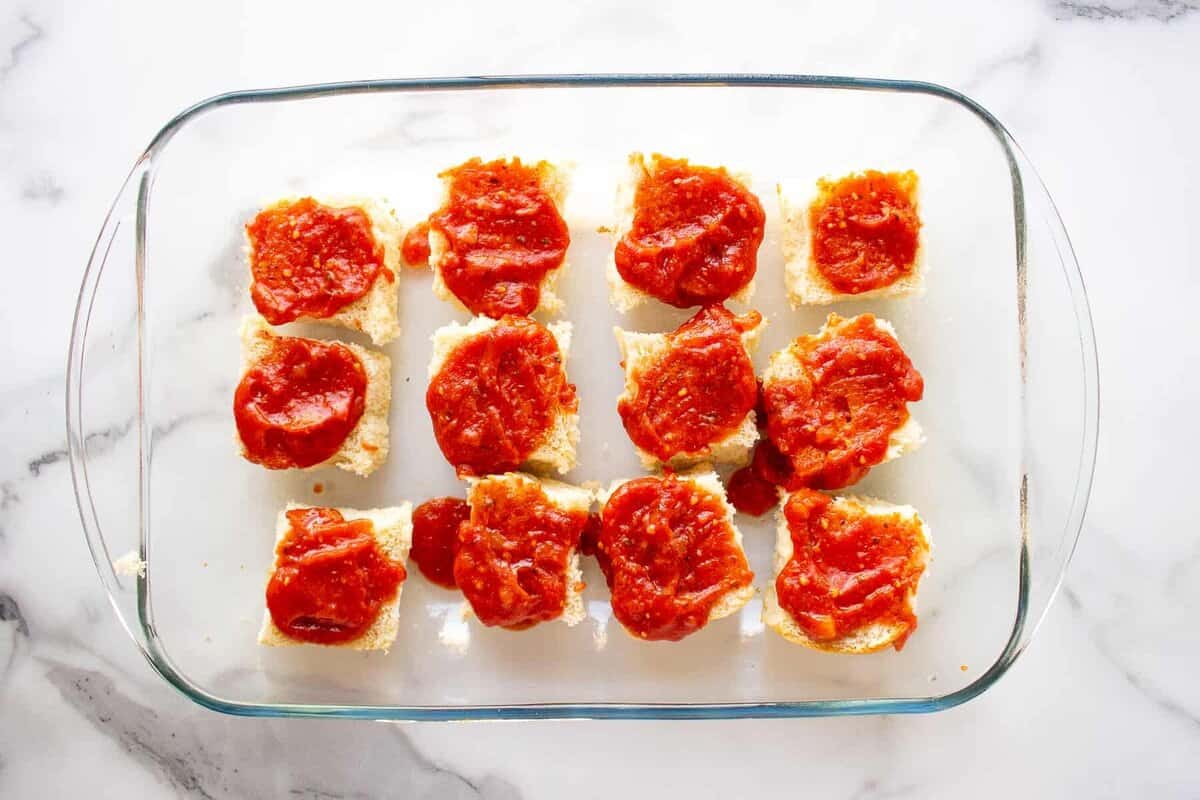 Sauce spread on bottom of Hawaiian rolls.