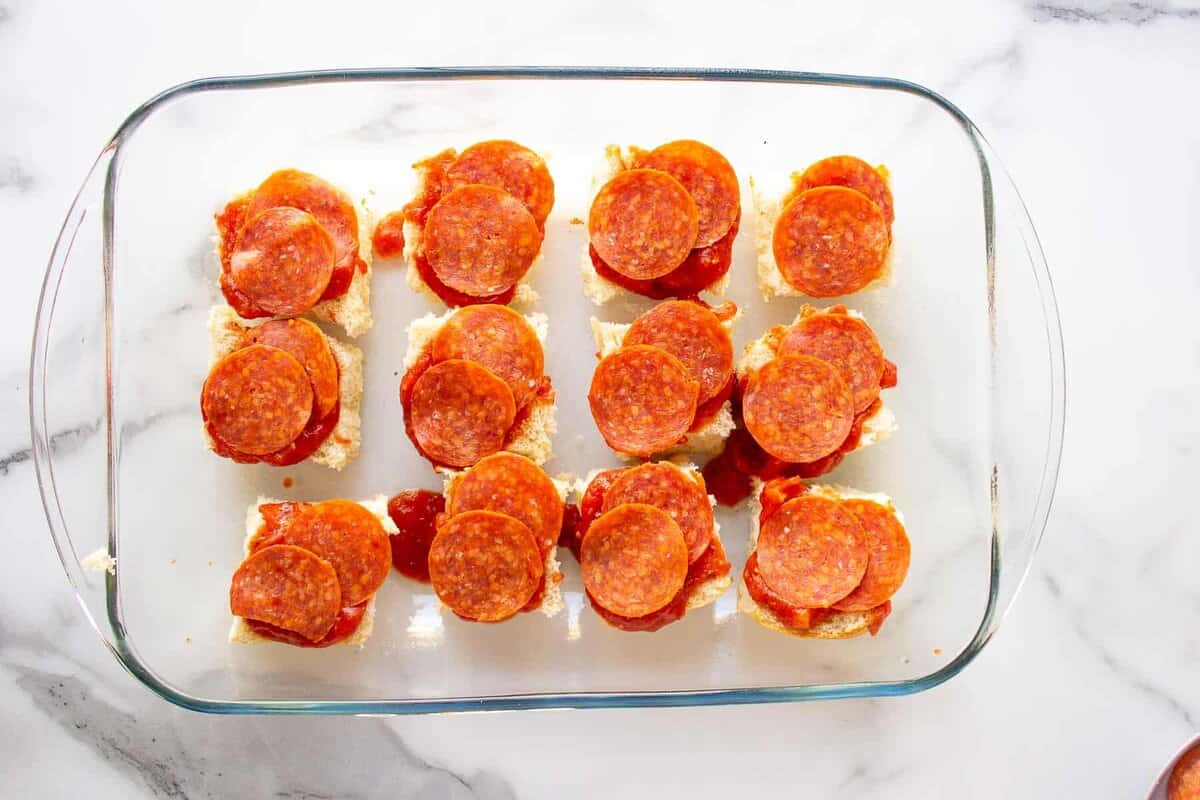 Pepperoni layered onto slider rolls.