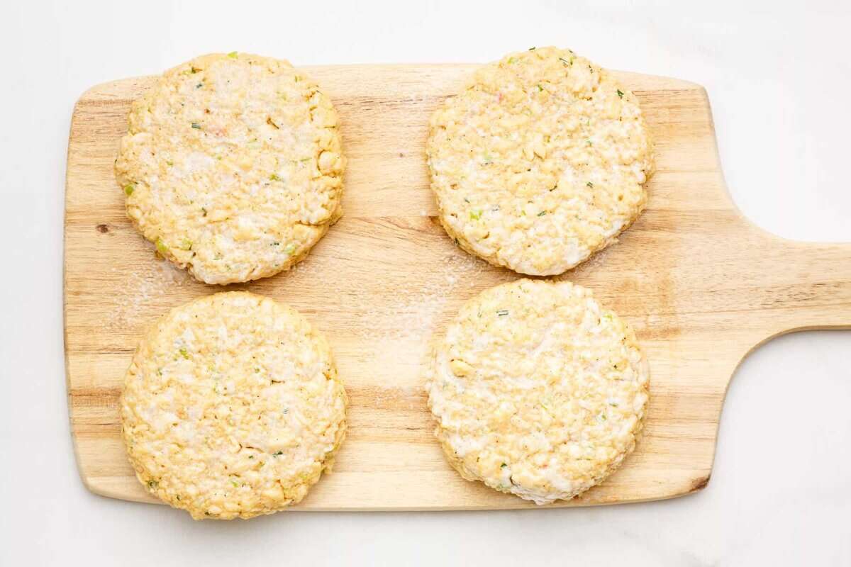 Crab cake patties on wooden board before cooking.