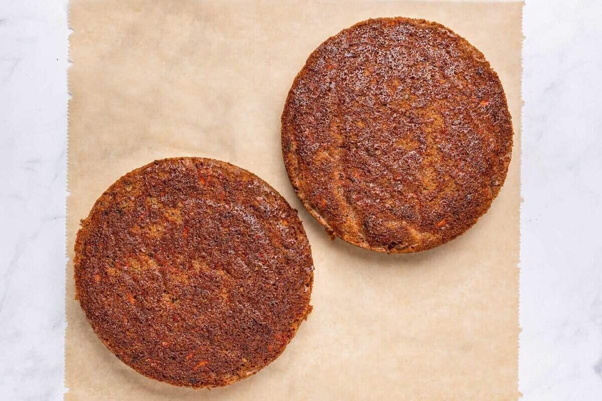 Two layers of carrot cake on parchment paper.