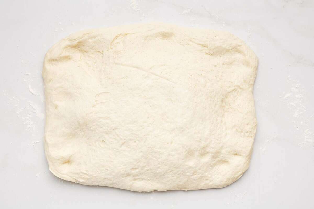 White sandwich bread dough patted into rectangle.