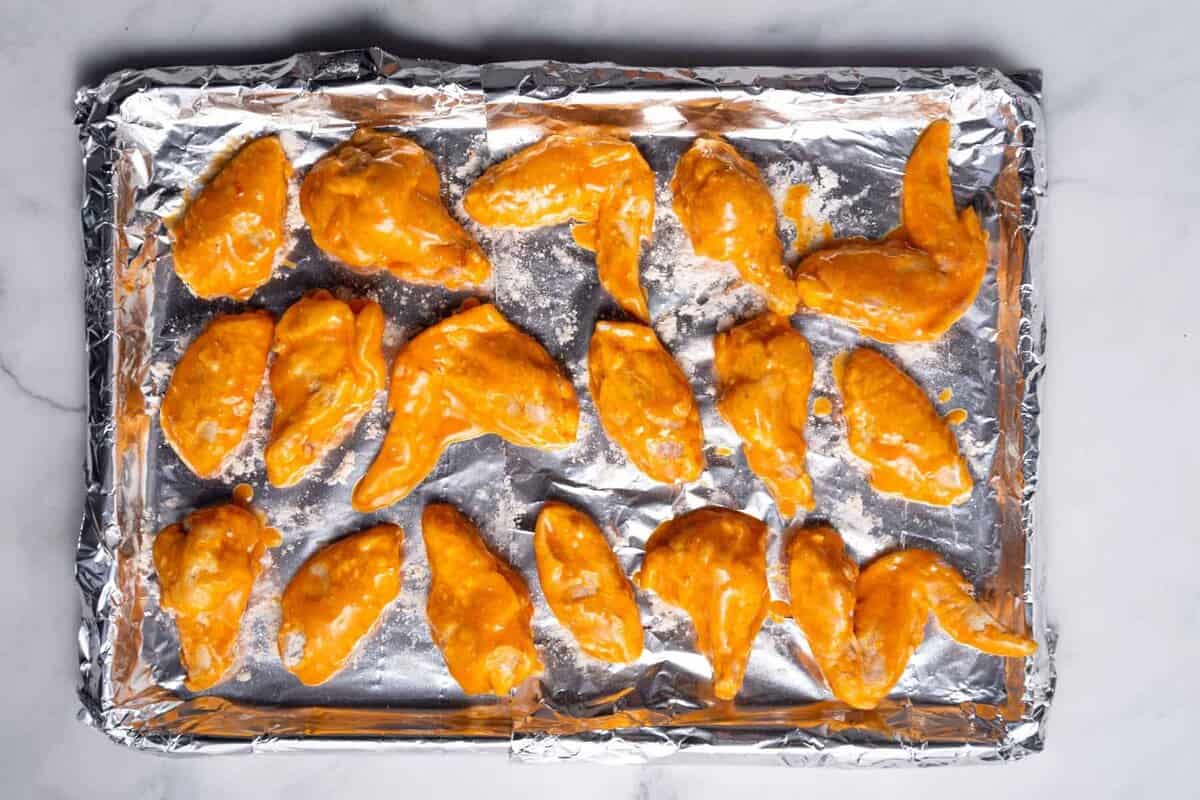 Buffalo chicken wings on pan before baking.