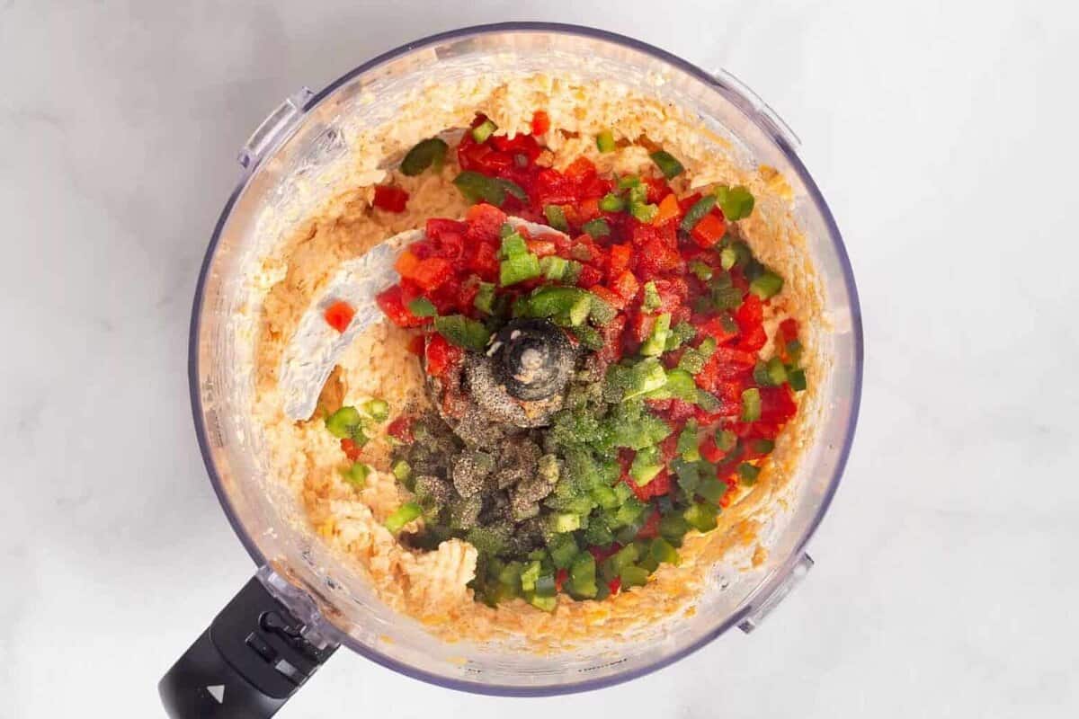 Peppers added to pimento cheese in food processor.