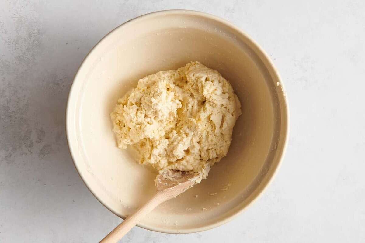 Biscuit dough in bowl with wooden spoon.