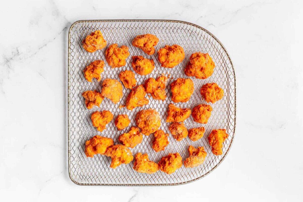 Crispy buffalo cauliflower in air fryer basket.