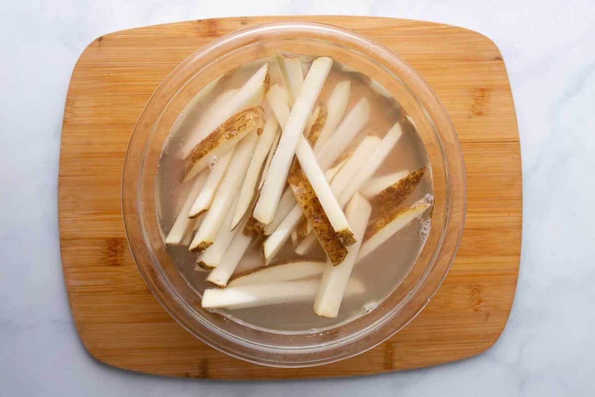 Raw fries soaking in bowl of water.
