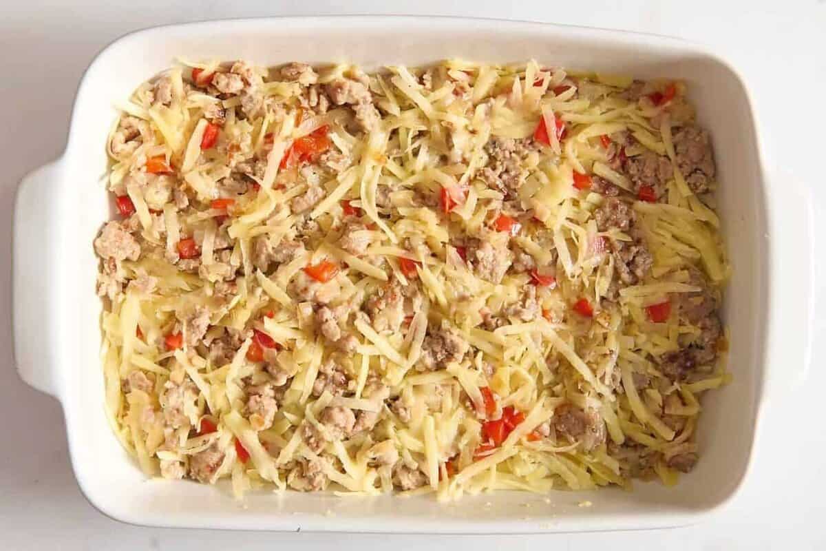 Hashbrowns, veggies, and sausage in casserole dish.